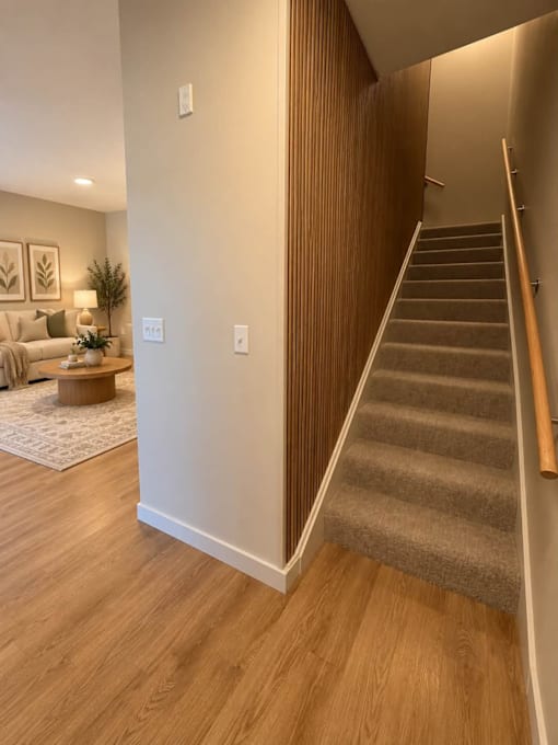 A staircase with a wooden handrail and carpeted steps leads to an upper level.