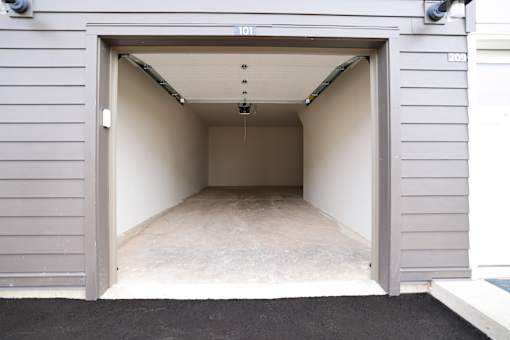 A garage door is open to reveal a clean, empty garage inside.