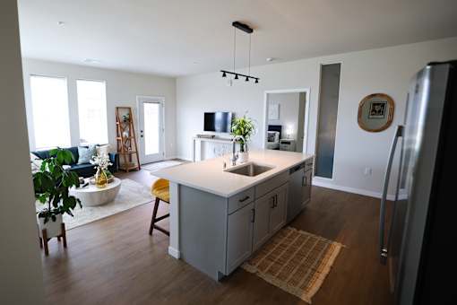 A kitchen with a refrigerator, sink, and a dining table with chairs.