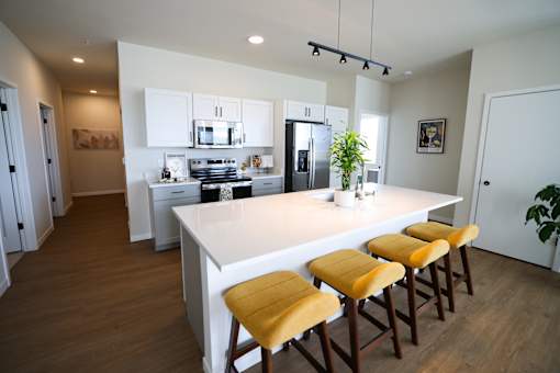 A kitchen with a white island and yellow bar stools.