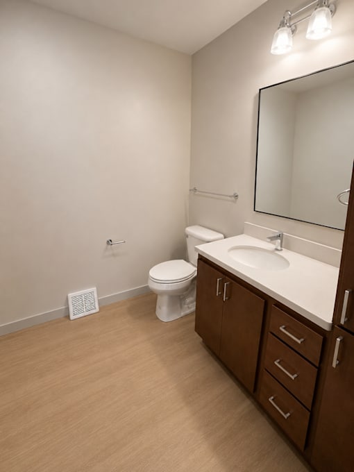 A bathroom with a toilet, sink, and mirror.