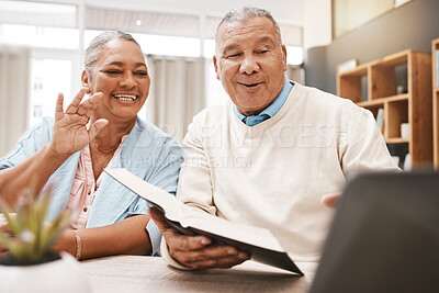 Two people sitting at a table, one holding a book and the other gesturing with their hand.