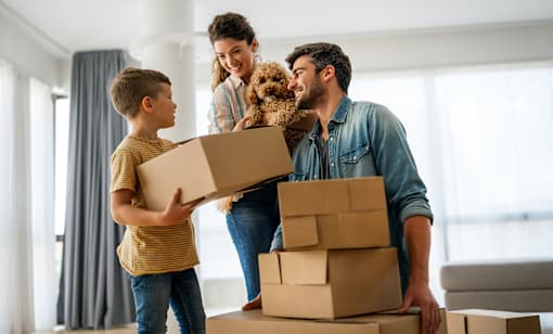 A family is moving into a new home with boxes and a dog.
