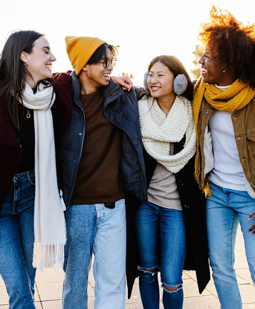 Four friends are standing close together and laughing.