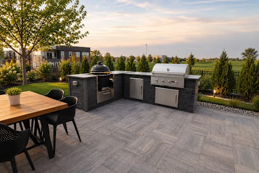 A patio with a table and chairs and a grill.