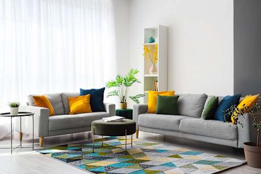 A living room with a sofa, a small table, and a colorful rug.