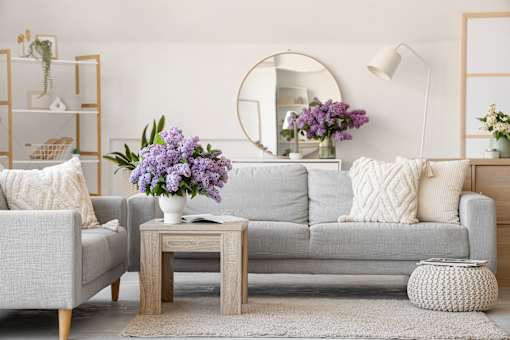 A living room with a couch, a coffee table, and a round mirror on the wall.