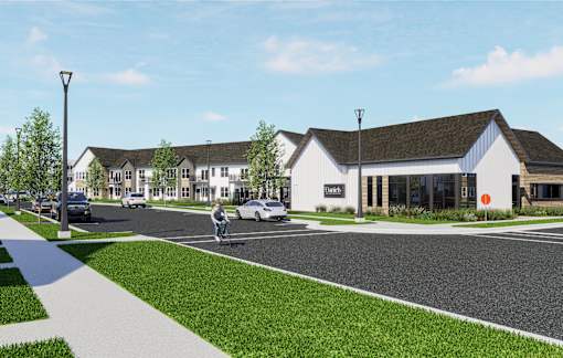 A street view of a building with a white facade and a green lawn in front at The Daniels at Northern Gateway Apartments, Saukville 53080