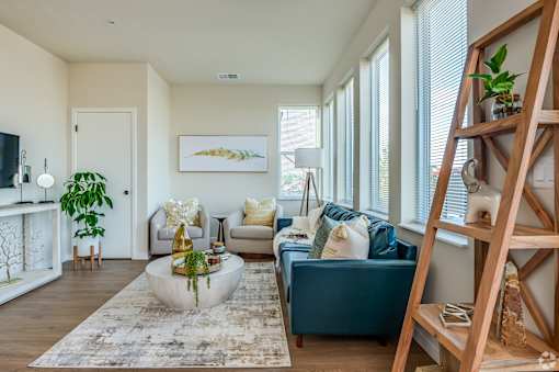 A living room with a blue couch and a wooden ladder.