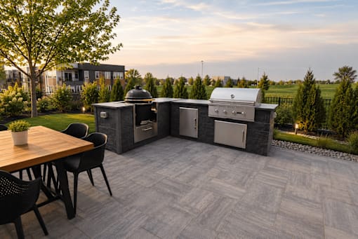 A patio with a table, chairs, and a grill.