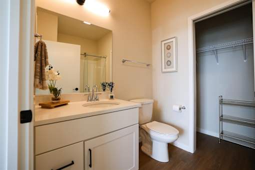A white toilet sits in a bathroom next to a sink and a mirror.