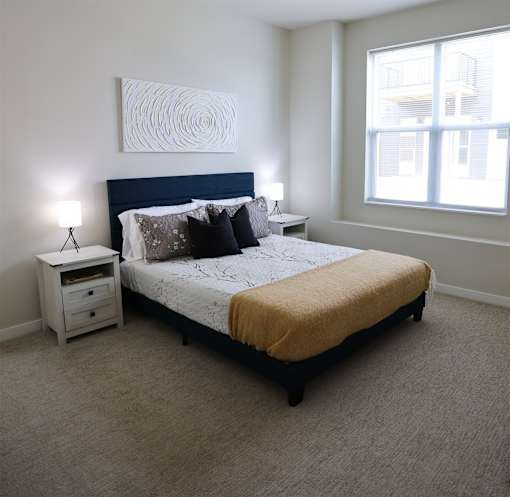 A bedroom with a bed, nightstand, and a painting on the wall.