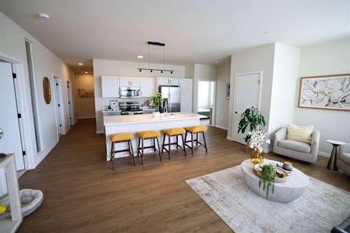 A modern kitchen with a white island and wooden floors.