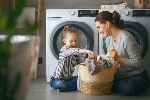 A woman and a child are doing laundry together.