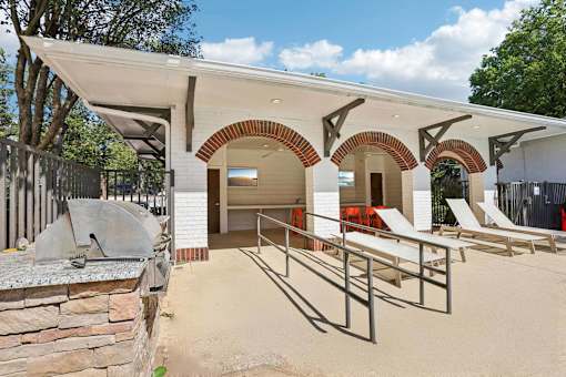 A building with a white roof and arched openings has a concrete wall in front of it.
