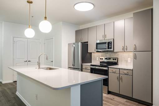 A kitchen with a white countertop and grey cabinets.