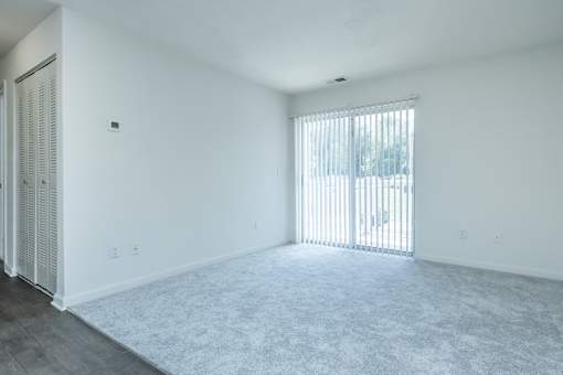 A room with white walls and a window with blinds.