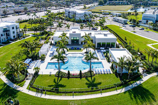 A large white building with a pool in the middle of a green lawn.