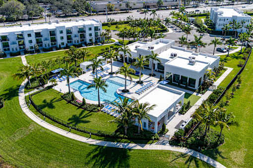 A large white building with a pool in front of it.