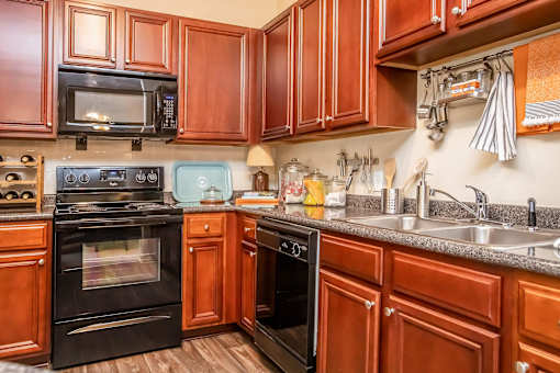A kitchen with brown cabinets and black appliances.