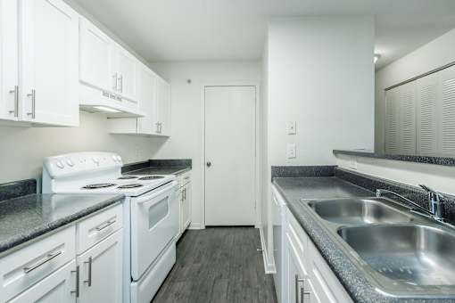 A kitchen with white cabinets and a stove top oven.