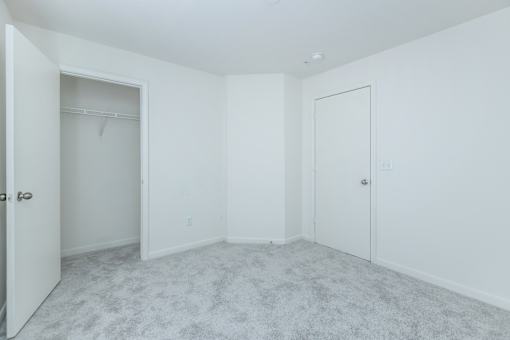 A white room with a carpeted floor and two doors.