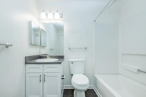 A white bathroom with a toilet, sink, and bathtub.