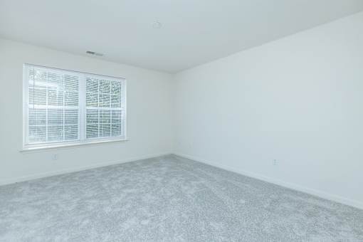 A room with a window and carpeted floor.