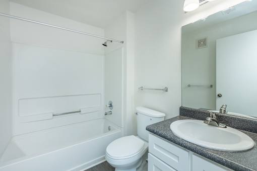 A white bathroom with a toilet, sink, and bathtub.