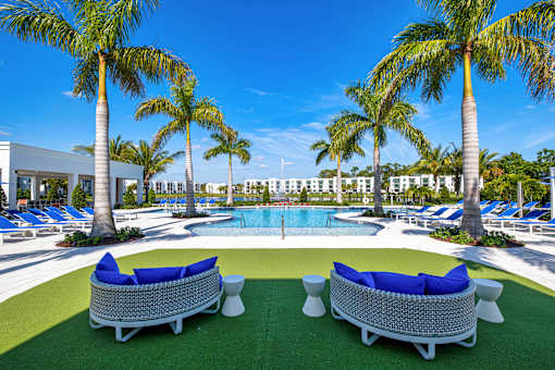 A pool surrounded by palm trees and lounge chairs.