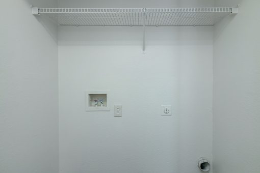 A white wall with a small picture frame and two switches.