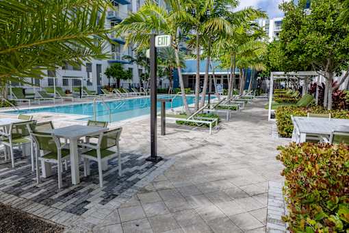 A pool area with chairs and tables.