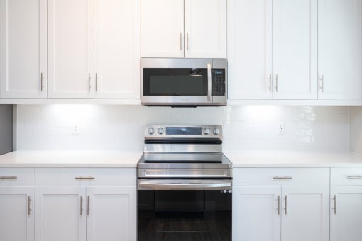 a kitchen with white cabinets and a stainless steel stove