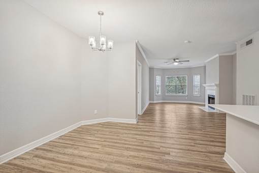 A room with wooden flooring and a chandelier hanging from the ceiling.