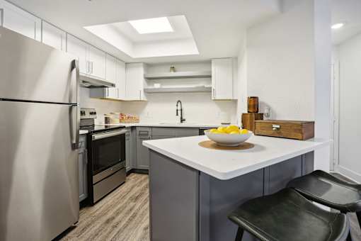 Atlanta, GA, Apartments Near Piedmont Park - Virginia Highlands -  Kitchen with Hardwood Floor, Granite Countertops, Stainless Steel Appliances, and Island Counter with Bar Seating.