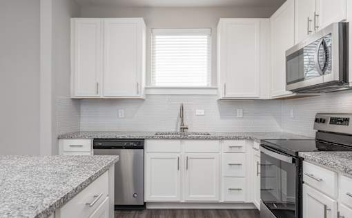 A kitchen with white cabinets and a granite countertop.