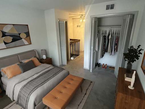 A bedroom with a bed, a bench, and a painting on the wall.