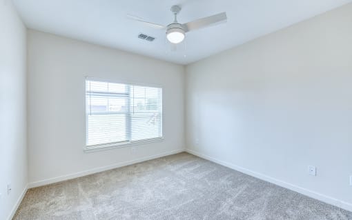 an empty room with a ceiling fan and a window