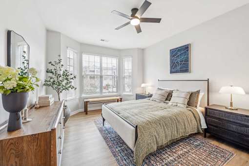 A bedroom with a bed, a ceiling fan, and a wooden dresser.