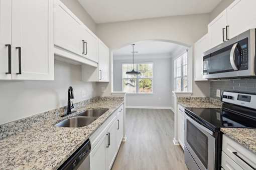 A kitchen with granite countertops and white cabinets.