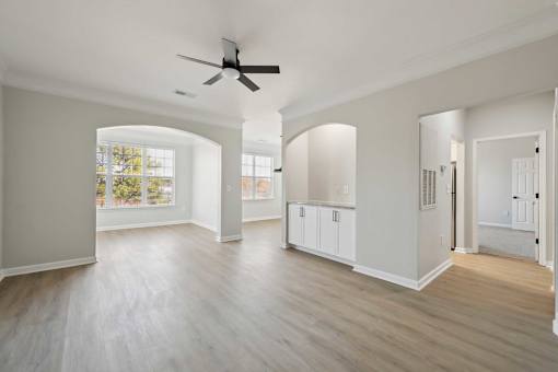 A spacious room with a ceiling fan and light wood flooring.