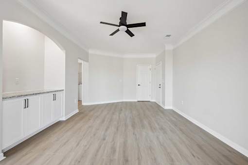 A spacious room with a ceiling fan and light wood flooring.