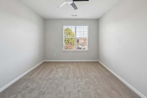 A room with a window and a fan on the ceiling.