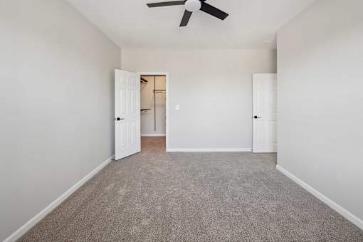 A room with a ceiling fan and carpeted floor.