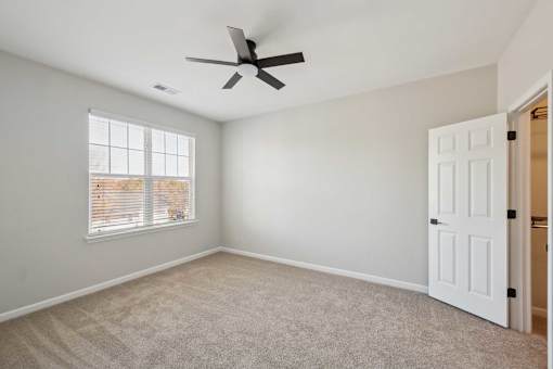 A room with a ceiling fan and a window with blinds.