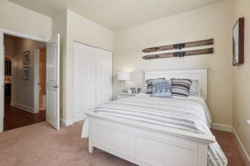 A bedroom with a large bed and a pair of skis on the wall.