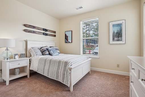 A bedroom with a bed, nightstand, and a window.