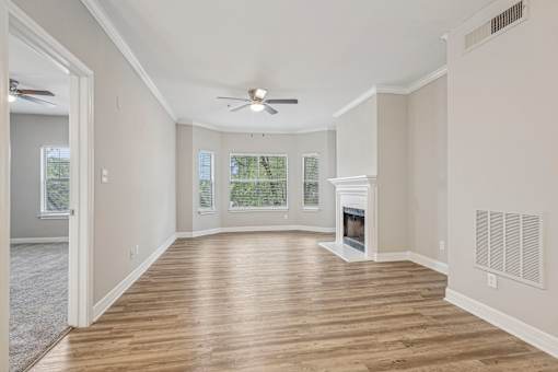 A spacious living room with a fireplace and a ceiling fan.