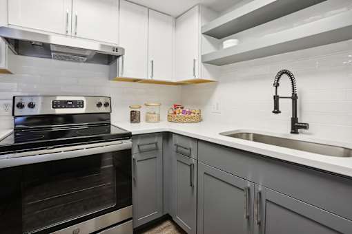 A modern kitchen with a stove, sink, and cabinets.