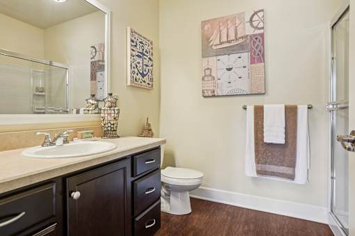 A bathroom with a toilet, sink, and a painting on the wall.